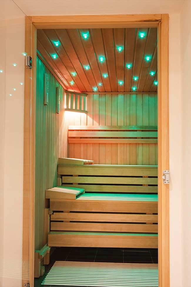 Auf dem Bild sieht man den Eingang zu einer kleinen Sauna, welche mit grünem licht beleuchtet wird.