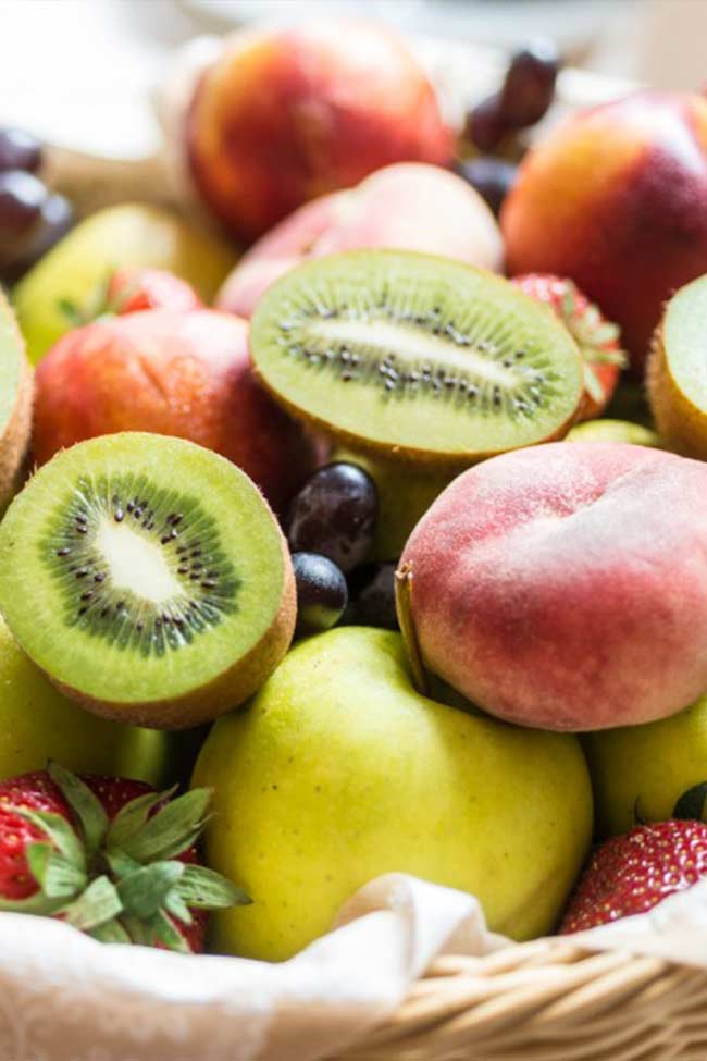 Obstschale mit Pfirsichen, Kiwis, Äpfeln und Erdbeeren