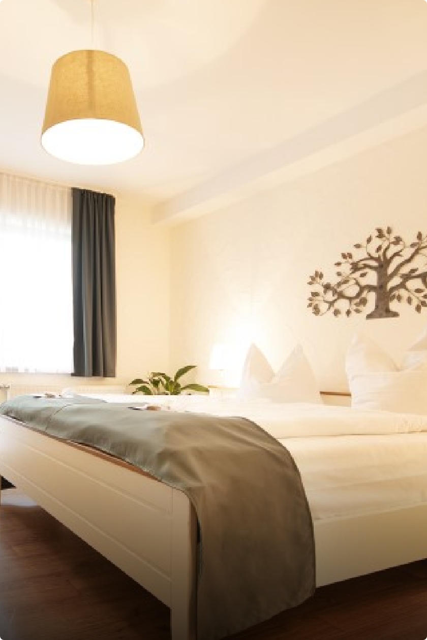 Landart Wohlfühl-Doppelzimmer mit Doppelbett im Focus, mit weißen Matratzen- und Kissenüberzug sowie einer grünen Überdecke.