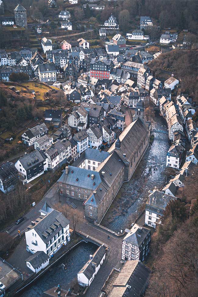 Hier sieht man eine Luftaufnahme von einem Dorf. Durch das Dorf fliest ein Fluss. 