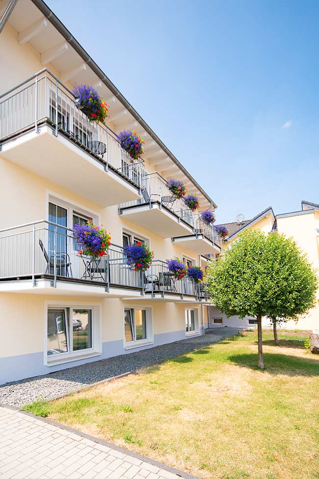 Blick auf den Zimmerkomplex des Hotels. Die Balkone sind mit Blumen bepflanzt.